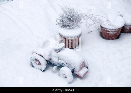 Auf Blumentöpfe und Spielzeug Traktor des Kindes im Schnee bedeckt als Blizzard auf ein Januar winter Tag fällt, Sheffield UK Stockfoto