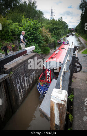 Zwei Frauen ihre 15-04 in einem Schloss, während ein Mann bereitet die Verriegelung auf dem Coventry Canal, Staffordshire, England zu lenken. Stockfoto