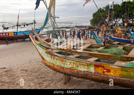 Schuljahre, Fischerdorf am Golf von Guinea, in der Nähe von Accra, Ghana, Afrika. Einheimische Fischerboote auf den Strand ziehen. Stockfoto