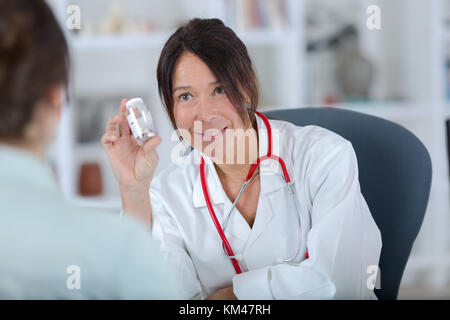 hübschen weiblichen Arzt zeigen Pillen für Patienten Stockfoto
