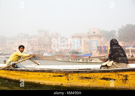 Eine ausländische Touristen genießen den Blick auf ghats durch den heiligen Fluss Ganges Touren auf einem hölzernen Ruderboot, Varanasi, benares, Kashi, Indien Stockfoto