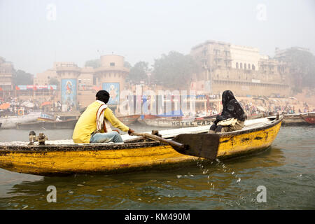 Eine ausländische Touristen genießen den Blick auf ghats durch den heiligen Fluss Ganges Touren auf einem hölzernen Ruderboot, Varanasi, benares, Kashi, Indien Stockfoto