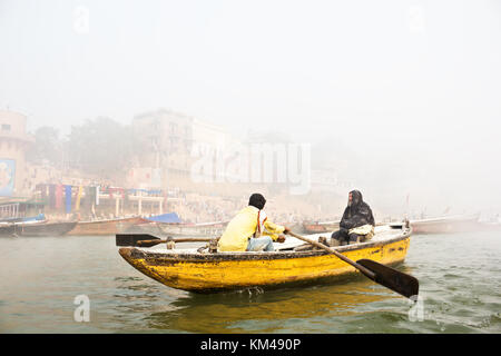 Eine ausländische Touristen genießen den Blick auf ghats durch den heiligen Fluss Ganges Touren auf einem hölzernen Ruderboot, Varanasi, benares, Kashi, Indien Stockfoto