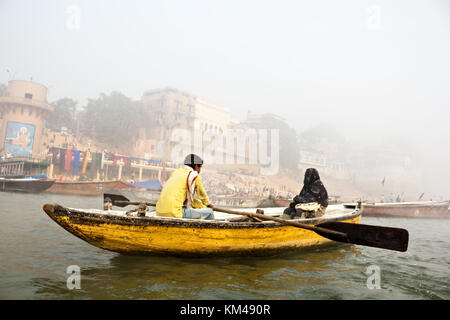 Eine ausländische Touristen genießen den Blick auf ghats durch den heiligen Fluss Ganges Touren auf einem hölzernen Ruderboot, Varanasi, benares, Kashi, Indien Stockfoto