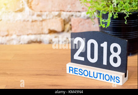 Neues Jahr 2018 Entschließungen zu blackboard anmelden und grüne Pflanze auf Holz Tisch an der Wand. Stockfoto