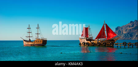 Zwei alte Holzschiffe. Einer von ihnen mit Red Sails ist am Pier. Stockfoto