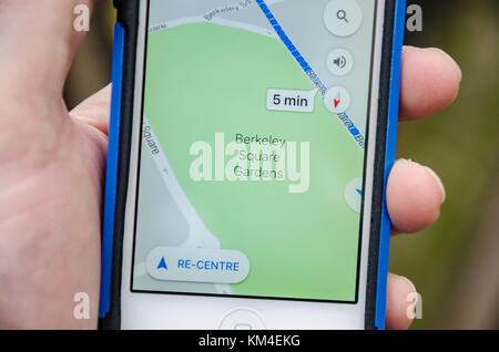 Nahaufnahme einer Hand, die ein iPhone hält, während die Google Maps App aktiv ist und die Berkeley Square Gardens im Zentrum von London zeigt. Stockfoto