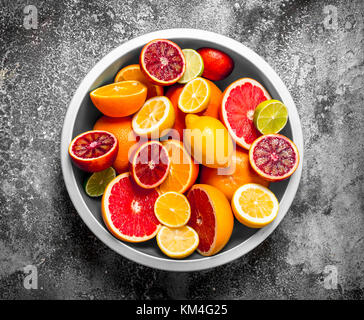 Aufgeschnittene Zitrusfrüchte in eine große Schüssel geben. Auf rustikalen Hintergrund. Stockfoto