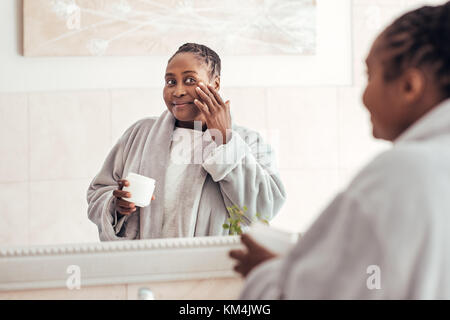 Junge afrikanische Frau Anwendung Gesichtscreme im Badezimmer Stockfoto