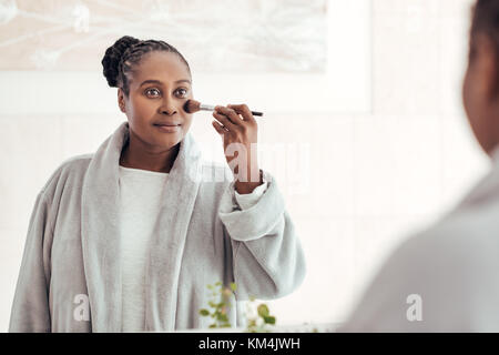 Afrikanische Frau Anwendung Make-up zu Ihrem Gesicht in einem Badezimmer Stockfoto