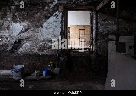 Ein traditionelles Haus mit Steinmauern renoviert. Blick durch eine Tür, Schritte zu einer beleuchteten Innenraum. Stockfoto