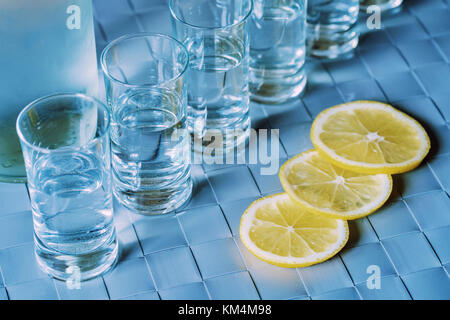 Vodka Shot Glas und Zitrone auf blaue Fläche Stockfoto