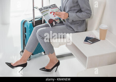 7/8 Schuß von Reife Geschäftsfrau mit Magazin warten auf Reise Stockfoto