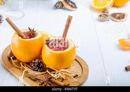 Glühwein - ungewöhnlich in Orange serviert. Heißer Winter trinken mit Beeren, Orangen, Gewürzen, Zimt auf den Holztisch mit Zutaten und Gewürze. Stockfoto