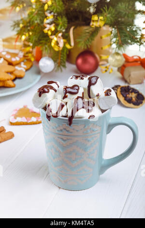 Traditionelle heiße Schokolade mit Marshmallows und Schokolade auf die weiße Holztisch mit Weihnachtsbaum, Dekor, Geschenkboxen, Cookies und Gewürzen. Chris Stockfoto