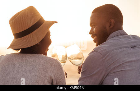 Gerne afrikanische Paar Wein trinken und beobachten den Sonnenuntergang am Strand Stockfoto
