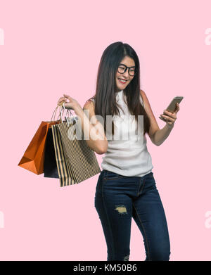 Glückliche junge asiatische Frau einkaufen in glückliches Gefühl und halten das Produkt Papiertüte auf dem rosafarbenen Pastelltönen Hintergrund, gehören Freistellungspfad Stockfoto