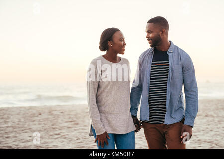 Lächelnd afrikanischen Paar zusammen am Strand bei Sonnenuntergang Stockfoto