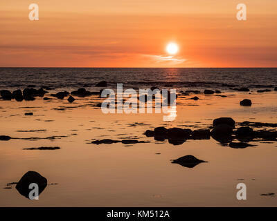 Sonnenuntergang und Küstenlinie Felsbrocken im Wasser in der Nähe von Saint Pauls, Gros Morne National Park, Neufundland, Kanada. Stockfoto