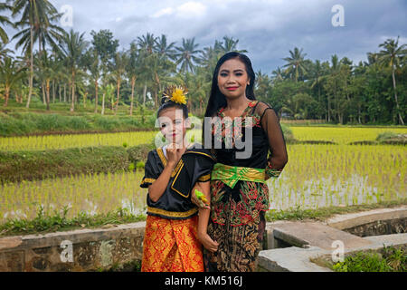 Indonesische junge Frau und Mädchen in schönen traditionellen Kleid in den Reisfeldern in der Nähe von tetebatu auf der Insel Bali, Indonesien Stockfoto