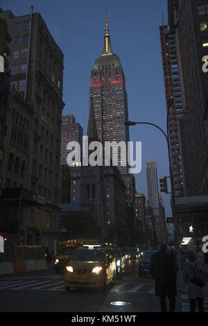 Blick nach Norden bis 5th Avenue, die 1854 Marmor Stiftskirche vorbei am Empire State Building mit seiner Krone in der Dämmerung in New York City angezündet. Stockfoto