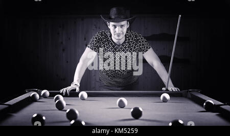 Ein Mann mit einem Bart spielt eine große Billard. Partei in einem 12-Fuß-Pool Stockfoto