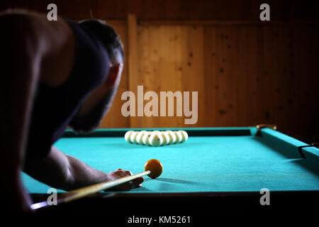 Ein Mann mit einem Bart spielt eine große Billard. Partei in einem 12-Fuß-Pool Stockfoto