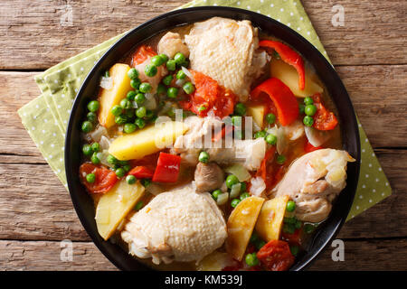 Stücke von Huhn Eintopf mit Kartoffeln, Paprika, Tomaten, Erbsen und Zwiebeln close-up in einer Schüssel auf den Tisch. horizontal oben Ansicht von oben Stockfoto