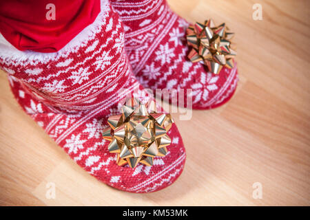 Rot gestrickt Stiefel mit Fell voller Bänder und Holzboden. Weihnachten personal Konzept Stockfoto