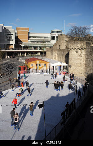 Kunsteisbahn am Einkaufszentrum Westquay Southampton, England. Im Rahmen der Weihnachtsfeier in der Stadt neben der mittelalterlichen Stadtmauer. Stockfoto