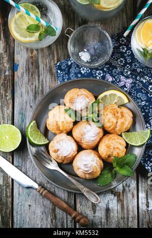 Jahrgang Teller mit hausgemachten Kuchen Windbeutel serviert mit Limonade auf alten Holztisch Stockfoto