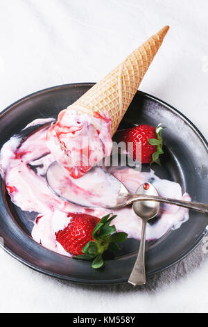 Wafer Kegel mit Erdbeereis mit Sirup, Löffel und frische Erdbeeren auf vintage Teller über weiß Textil. Stockfoto