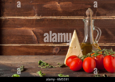 Wet Red Cherry Tomaten und Käse Parmesan auf Holztisch mit Olivenöl in vintage Glasflasche Stockfoto