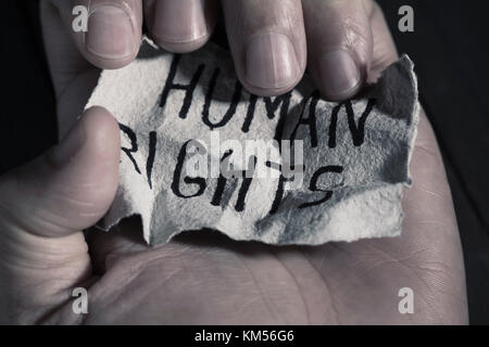 Nahaufnahme der Hand eines jungen Mannes mit einem Stück Papier mit dem Text der Menschenrechte in Es geschrieben Stockfoto