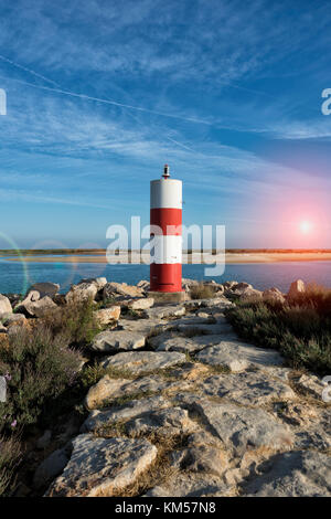 Rot-weiß gestreiften Leuchtturm/navigation Markierung auf einem Felsvorsprung in Fuseta, Portugal. Stockfoto