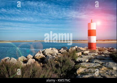 Rot-weiß gestreiften Leuchtturm/navigation Markierung auf einem Felsvorsprung in Fuseta, Portugal. Stockfoto