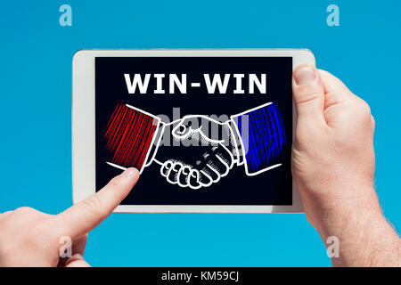 Mann hält ein tablet device zeigt Abbildung: viel Teamarbeit handshake Hände als Vereinbarung Konzept mit blauen Himmel im Hintergrund. Stockfoto
