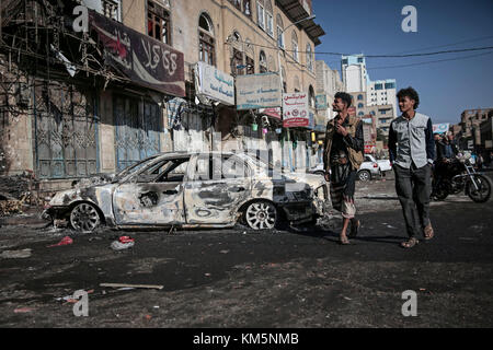 Sanaa, Jemen. Dezember 2017. Jemenitische Männer gehen an Autos vorbei, die bei Zusammenstößen zwischen Houthi-Kämpfern und Truppen des ehemaligen jemenitischen Präsidenten Ali Abdullah Saleh in Sanaa, Jemen, am 5. Dezember 2017 zerstört wurden. Saleh wurde am Montag von Huthi-Rebellen getötet. Quelle: Hani Al-ANSI/dpa/Alamy Live News Stockfoto