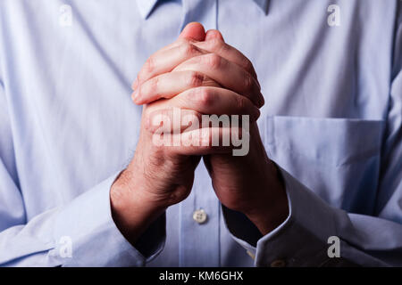 Nahaufnahme oder Nahaufnahme von Händen der Gläubigen reifer Mann beten. die Hände gefaltet, interlaced Finger in Anbetung zu Gott. Konzept für Religion, Glauben, Gebet ein Stockfoto