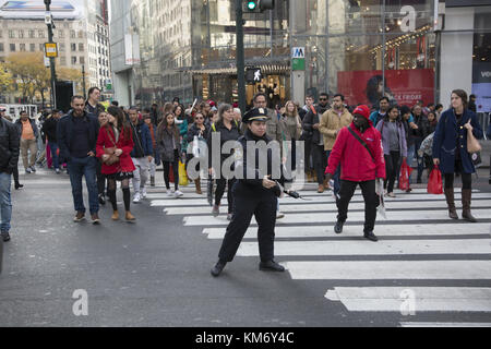 Weibliche Verkehrscop führt Autos und Fußgänger an der immer geschäftigen Kreuzung 34th Street und Broadway in New York City. Stockfoto