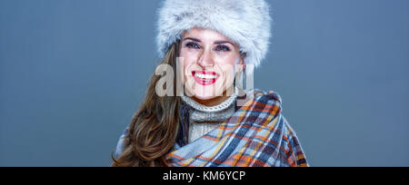 Wintersachen. Porträt von lächelnden trendige Frau in Pelzmütze isoliert auf kalten Blau Blick in die Ferne Stockfoto