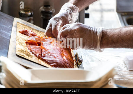 Männliche Hände stapeln Räucherlachs Schichten auf einem Tisch. Stockfoto