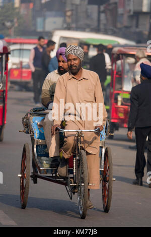 Punjabi sikh Mann mit Turban und Bart Pedale cycle rickshaw mit Passagier, in Amritsar, Indien Stockfoto