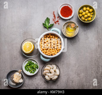 Verschiedene Zutaten zum Kochen in Schalen für kichererbsen Salat auf grauem Beton Hintergrund, Ansicht von oben, kopieren. gesunde, saubere Lebensmittel oder vegetarische Küche Stockfoto