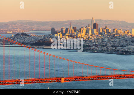 Abendsonne beleuchtet die San Francisco City High erhebt, mit der Golden Gate Bridge im Vordergrund, California, United States. Stockfoto