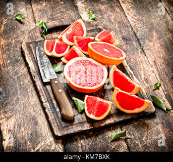 In Scheiben geschnittene Stücke von Grapefruit mit einem Messer. auf Holz- Hintergrund. Stockfoto