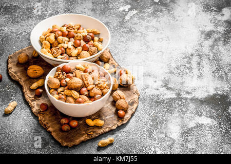 Eine Menge von Muttern in verschiedenen Schüsseln. Auf rustikalen Hintergrund. Stockfoto