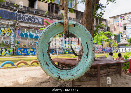 Einen alten Reifen schwingen in einer Stadt spielen Kinder Park mit alten Risse Farbe hängen von einem Baum mit einem dicken Seil. Stockfoto