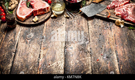 Rohes Fleisch Hintergrund. rohes Schweinefleisch mit einer Vielzahl von Kräutern und Gewürzen hacken. Auf dem alten Holztisch. Stockfoto