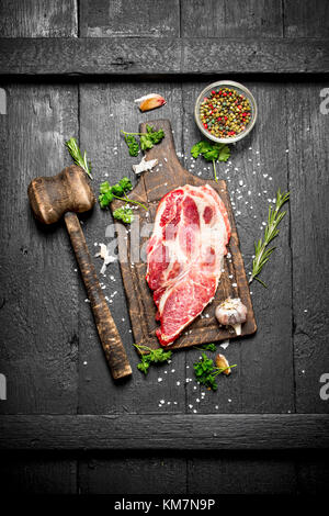 Rohes Fleisch Hintergrund. rohes Stück Steak mit Rosmarin und Gewürzen. Auf dem Schwarzen Tisch. Stockfoto